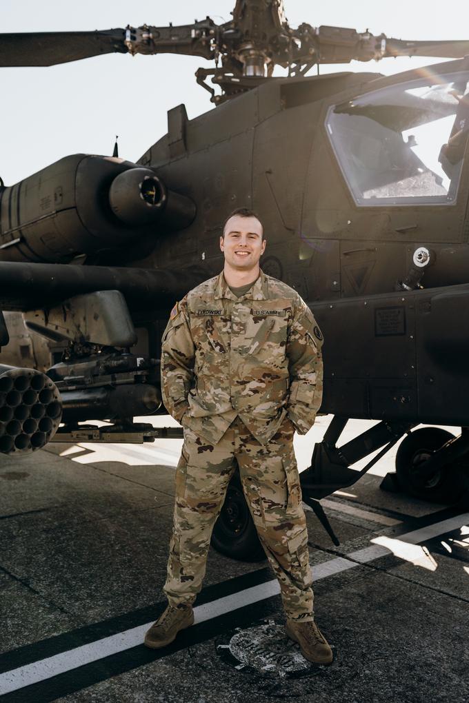 Andrew Lekowski in Army uniform standing beside an AH-64E Apache helicopter