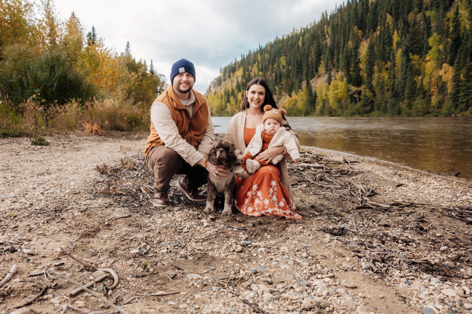 Andrew and Vivian Lekowski with their child and dog beside an Alaska river